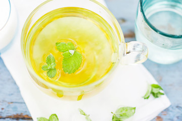 Cold fresh mint leaf tea, mint tea with ice cubes in a glass cup on a wooden table, cold mint beverage, healthcare and healthy eating concept