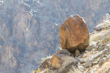 A large boulder perched on an edge of the mountainside