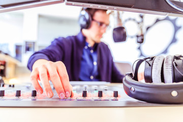 Radio moderator is sitting in a modern broadcasting studio and talking into the microphone