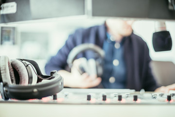 Radio moderator is sitting in a modern broadcasting studio and talking into the microphone