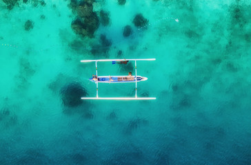 Boat on the water surface from top view. Turquoise water background from top view. Summer seascape from air. Gili Meno island, Indonesia. Travel - image