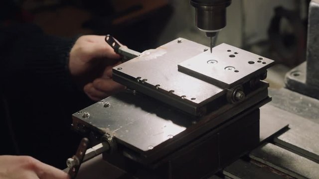 Worker is operating a soviet drill press machine with 2 axis support table