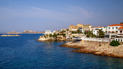 Fototapeta na wymiar Coastline in Marseille, rocky coast, relaxing people in a sunny summer day, mediterranean houses, summer holidays, southern France.
