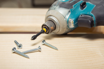 cordless screwdriver in wooden surface with screws