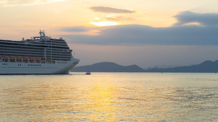 Fototapeta na wymiar Cruise liner - leaving the port in the evening with beautiful view on wide ocean with hills in the background 