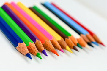 Close-up of a selection of Multi Colored pencils crayons, stick together arranged in a row line bar graph on white background, flat lay. Selective focus, blur image. Back to school creativity concept.