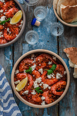 Shrimps saganaki with feta cheese on a plate on a table