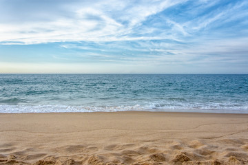 The beautiful view of the sandy ocean beach with bright blue cloudy sky