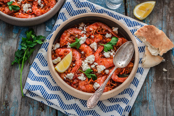 Shrimps saganaki with feta cheese on a plate on a table