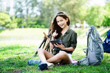 Teenage Woman travelers are sitting on tablet to shop online that involves hiking equipment. And order other items such as food, water, medicine. Summer vacations making you feel relaxed, happy