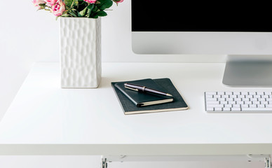 Mockup computer with keyboard, vase of flower and book on white table.