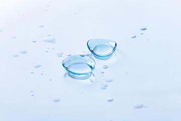 Contact lenses and water drops on light blue background. Eyewear, eyesight and vision, eye care and...