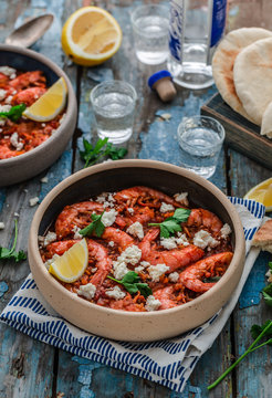 Shrimps saganaki with feta cheese on a plate on a table
