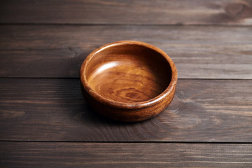 Obraz na płótnie Canvas Empty wooden bowl on brown table. Round salad-bowl. Tableware from natural material