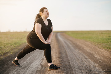 Cropped portrait of woman in sportswear training legs getting ready for running in the meadow, copy space. Healthy lifestyle, sport, weight losing, activity concept