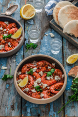 Shrimps saganaki with feta cheese on a plate on a table