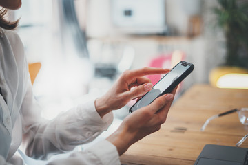 Female hands holding smartphone and touching screen.Businesswoman using mobile phone.Closeup on...