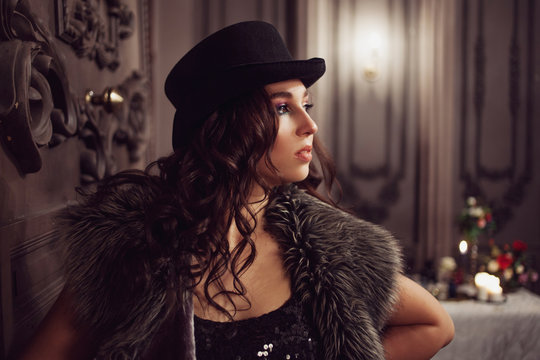 Beautiful young brunette woman in top hat, mysterious interior