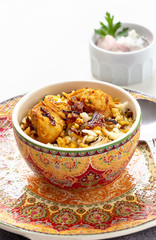 Halal Indian chicken Biryani served with yogurt tomato raita over white background. Selective focus