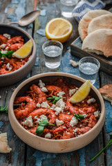 Shrimps saganaki with feta cheese on a plate on a table