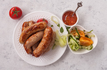 Grilled sausages with fresh vegetable salad and sweet and sour sauce.  Top view