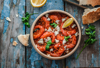 Shrimps saganaki with feta cheese on a plate on a table