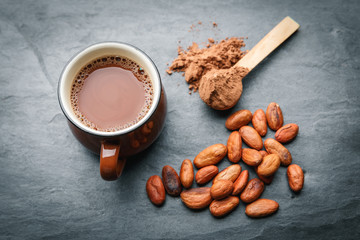 Brown cup of fresh cocoa drink with cocoa beans and powder