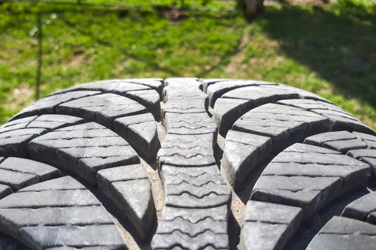 Close-up winter tire tread. Textured tire tread on green and bokeh background.