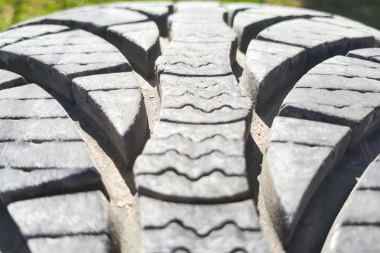 Close-up winter tire tread. Textured tire tread on green and bokeh background.