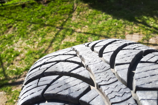 Close-up winter tire tread. Textured tire tread on green and bokeh background.