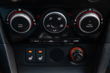 Fototapeta premium The interior of the car with a view of the dashboard, front seat heater buttons and climate-controle with light gray trim