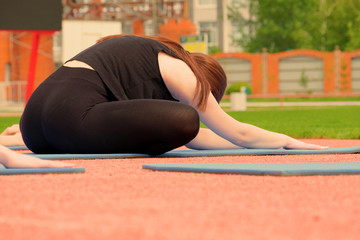 Close-up Girl doing exercise butterfly and stretches her back. Exercises for the splits. Fitness classes in the fresh air.
