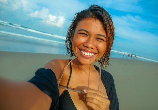 young happy and attractive Asian exotic woman on the beach taking selfie portrait with mobile phone smiling cheerful enjoying holidays trip at beautiful tropical island