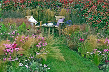 Corner of a cottage garden with outdoor eating and a display of grasses and flowers