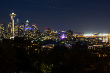 Obraz premium Night view of the Seattle skyline with the Space Needle and other iconic buildings in the background.