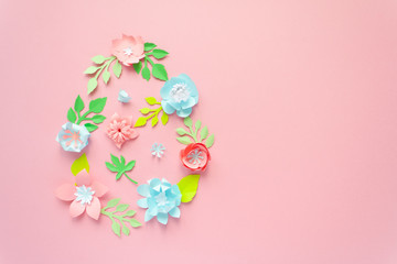 Easter egg made of paper flowers on pink background. Cut from paper.