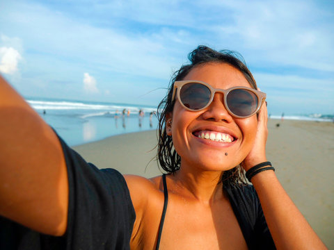 young happy and attractive Asian exotic woman on the beach taking selfie portrait with mobile phone smiling cheerful enjoying holidays trip at beautiful tropical island