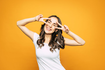 Happy as Larry! An orange background with a beautiful girl with curly brown hair, brilliant smile in white casual T-shirt in front of it.