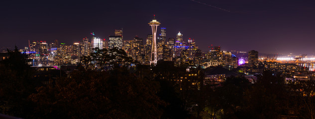 Panoramic night view of the Seattle skyline with the Space Needle and other iconic buildings in the background.