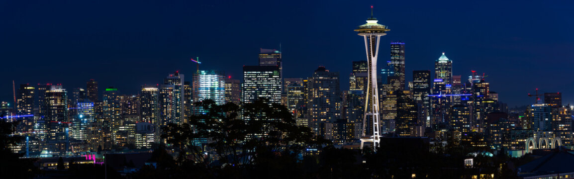 Panoramic night view of the Seattle skyline with the Space Needle and other iconic buildings in the background.