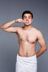 Fototapeta premium Joyful guy caring of hid dental health isolated on gray background!