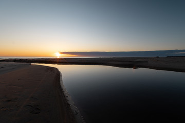 Fototapeta premium Red vivid sunset at the Baltic Sea with mirror like water - Veczemju Klintis, Latvia - April 13, 2019