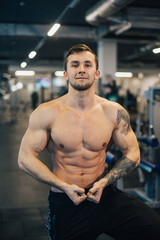 Fototapeta na wymiar Young athletic man with naked torso standing in gym