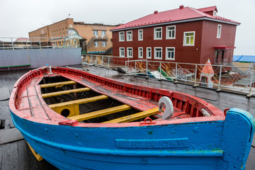 Fototapeta na wymiar Barentsburg, blue boat in front ot kindergarten buildings on an Arctic autumn day in Svalbard