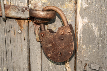 Old rusty closed lock without key. Vintage wooden door, close up concept photo