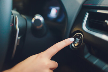 Car driver starting the engine keyless. Black. female hand.