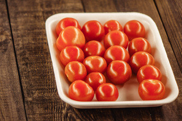 tasty cherry tomatoes on a wooden stand, wooden background