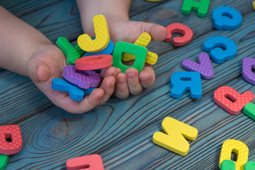 Letters of the English alphabet in the hands of a man on a wooden table background. preschool education.