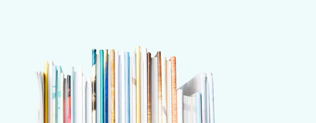 Close view of Stack of children's books on a pastel blue background. Long wide banner with copy...