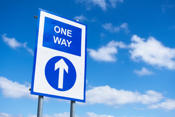 One way directional arrow sign against blue sky